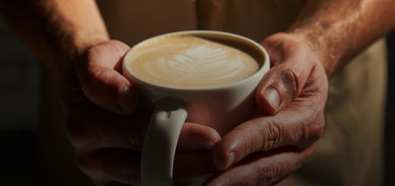Een close-up van handen die een kop Starbucks koffie vasthouden