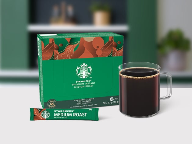 Starbucks® Premium Medium Roast oploskoffie in een glazen mok, samen met een sachet en verpakking