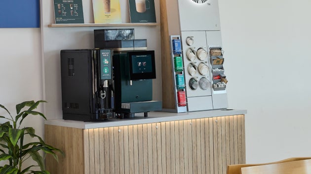 Een compact We Proudly Serve Starbucks koffiestation in een polikliniek van een ziekenhuis, voorzien van een zelfbedieningsko
