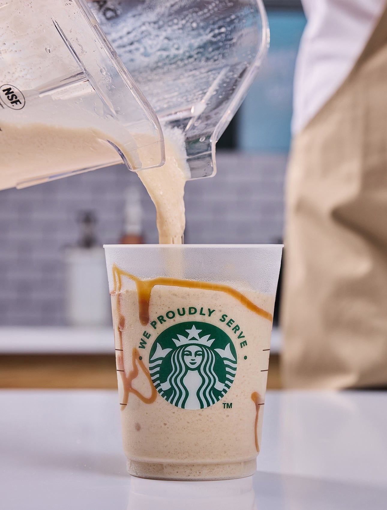 Une boisson We Proudly Serve Starbucks nappée de crème fouettée, avec un filet de chocolat ajouté par un barista.
