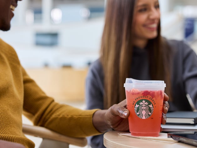 Un groupe d’amis souriants brandit trois boissons glacées Starbucks.