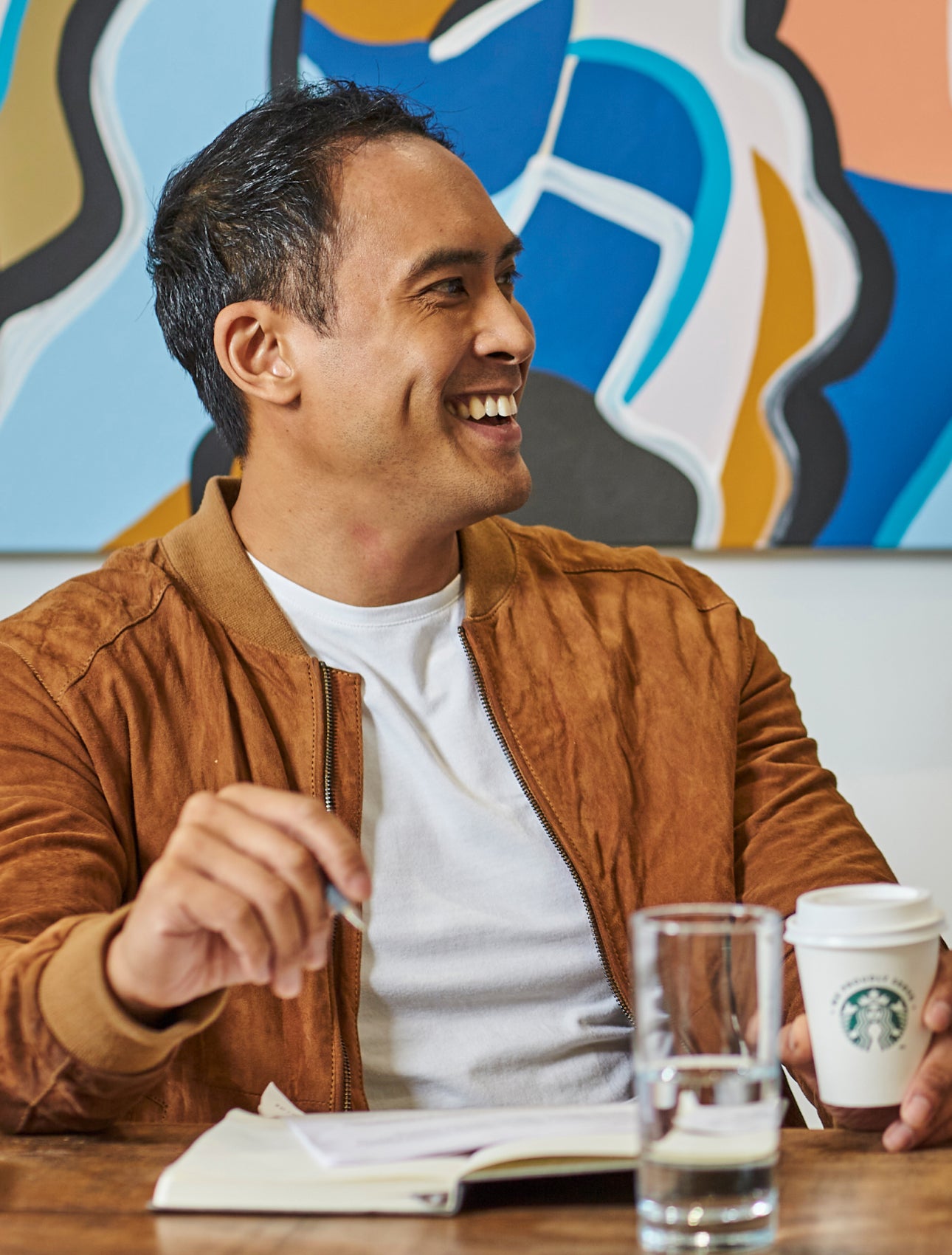Men sitting at a table holding We Proudly Serve Starbucks coffee