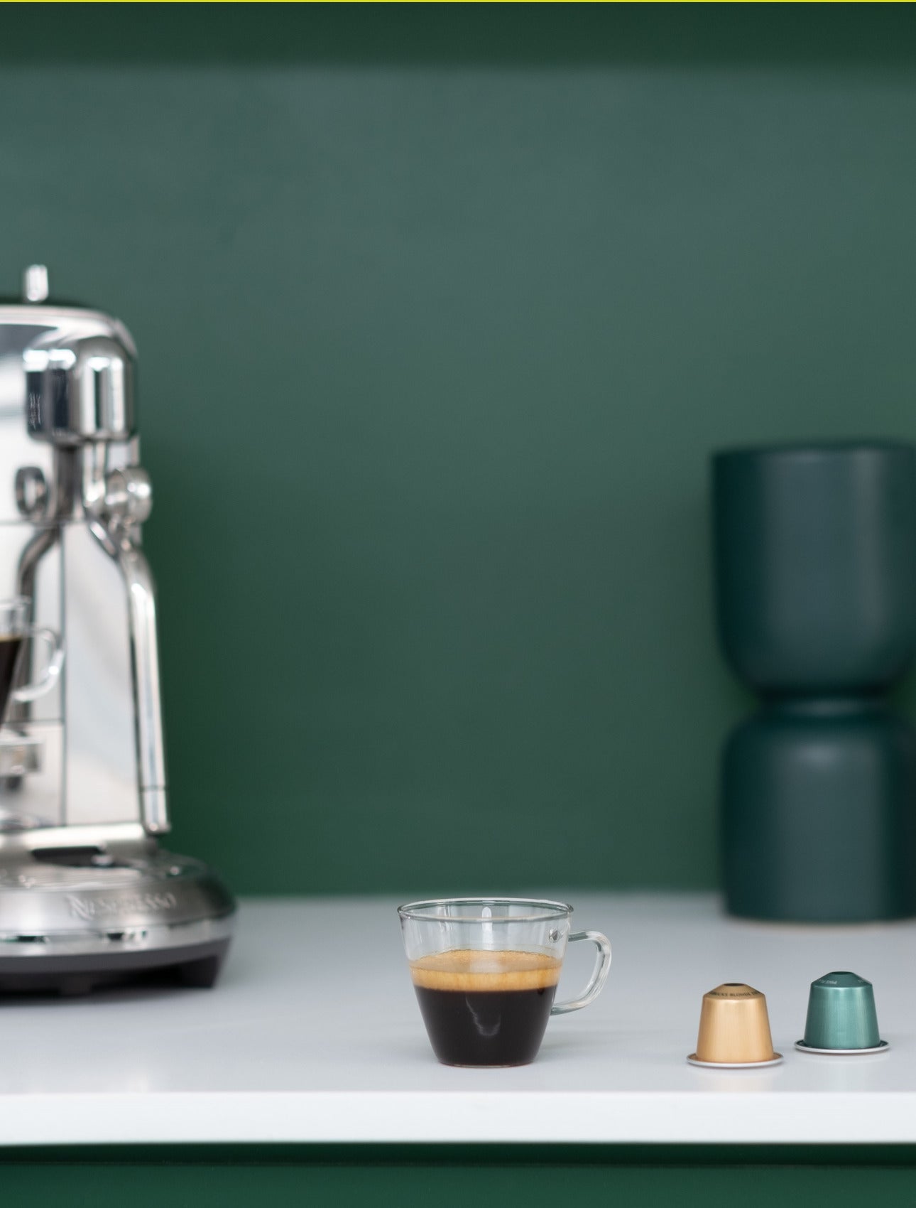 Espresso and We Proudly Serve Starbucks coffee capsules in front of Nespresso machine on counter top