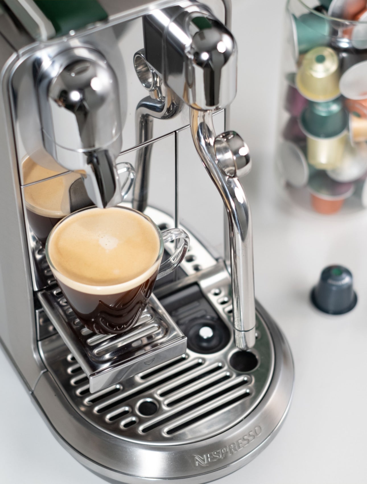 Nespresso machine with coffee and We Proudly Serve Starbucks capsules in the back