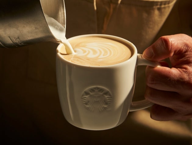 Pouring milk into a ceramic Starbucks mug to create latte art