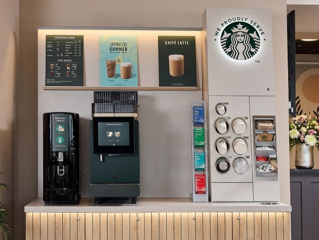 A We Proudly Serve Starbucks self-service coffee machine station