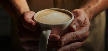 A close-up of hands holding a cup of Starbucks coffee