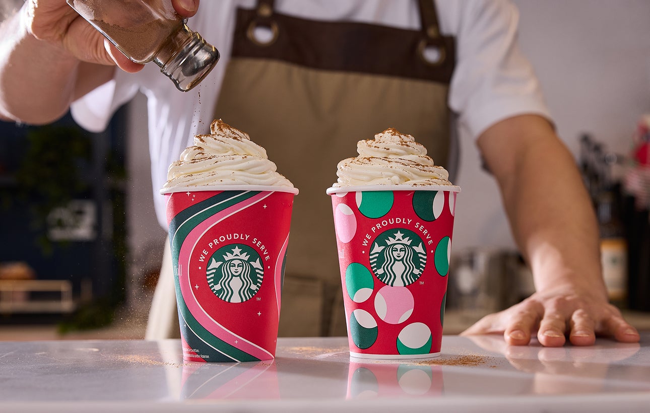 Twee Frappuccino® Gemixte Dranken in feestelijke We Proudly Serve Starbucks bekers, waarvan er één is bestrooid met kaneel. 