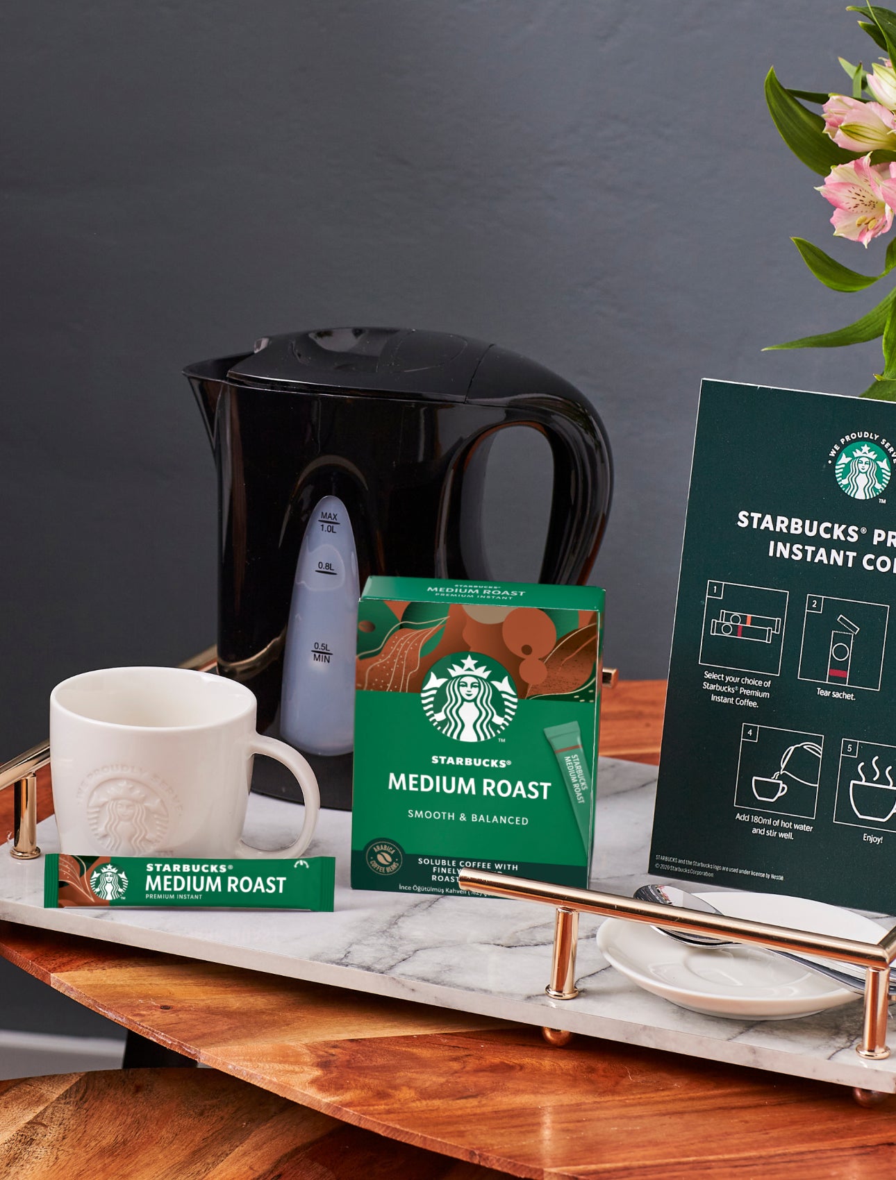 Een tafelblad met een We Proudly Serve Starbucks mok, Starbucks Premium oploskoffie en bereidingsinstructies