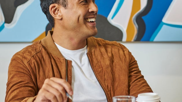 Mannen zitten aan een vergadertafel en houden bekers We Proudly Serve Starbucks koffie vast