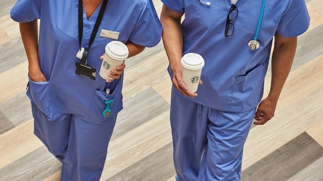 หมอ 2 คนเดินมาพร้อมถือกาแฟ Starbucks ในโรงพยาบาล